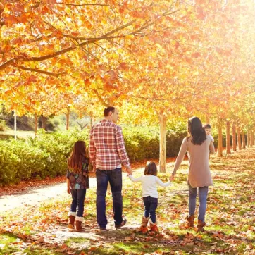 A family walking through a park in Autumn